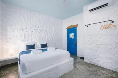 a white room with a bed and a blue door at Sweett Lemon Home in Patong Beach