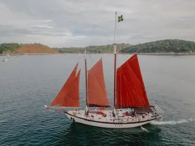 a sail boat with red sails in the water at Sjostrom in Ban Ko En