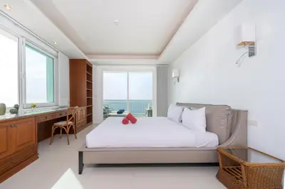 a bedroom with a bed and a desk and windows at Waterfront 16D seaview 2 BR apartment - 5 min walk to Karon beach in Karon Beach