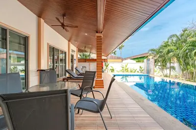 a patio with a table and chairs next to a swimming pool at Orchid Pool Villa Rawai in Rawai Beach