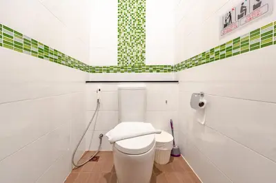 a bathroom with a toilet and a green and white wall at Orchid Pool Villa Rawai in Rawai Beach