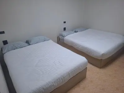 two twin beds in a room with white walls at Kami Guest House Patong in Patong Beach