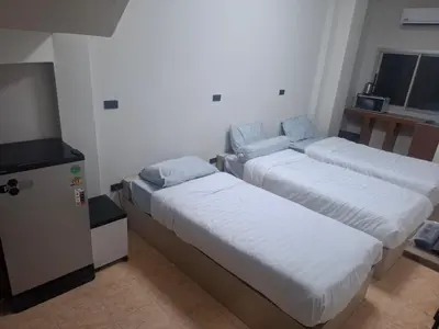 a room with three beds and a television in it at Kami Guest House Patong in Patong Beach