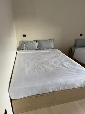 a bed in a small room with a white bedsheet at Kami Guest House Patong in Patong Beach