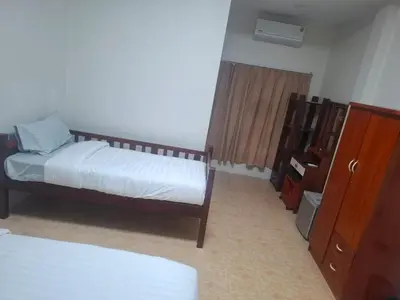 a bedroom with two beds and a dresser in it at Kami Guest House Patong in Patong Beach