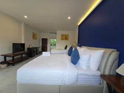 a bedroom with a large white bed with a blue wall at The Simple Place - King and Twin in Klong Muang Beach