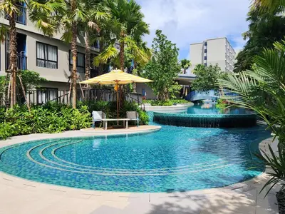 a swimming pool with a table and an umbrella at Cozy Palm Haven apartment in Kathu