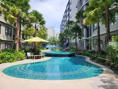 a swimming pool in a courtyard with palm trees at Cozy Minimalist room in Kathu
