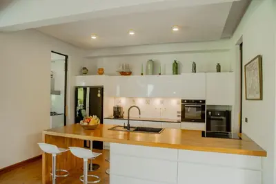 a kitchen with white cabinets and a wooden counter top at 4BR Laguna Golf View Pool Villa Retreats Phuket in Laguna Phuket