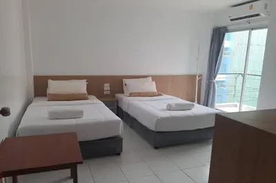 a bedroom with two beds and a table and a window at Wow Boutique Patong in Patong Beach