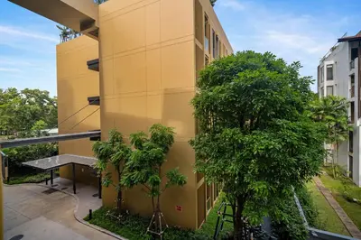 a yellow building with a table and trees next to it at Laguna Beachside Block 2 by Banyan Living in Bang Tao Beach