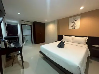 a bedroom with a large white bed and a desk at Patong gray house in Patong Beach