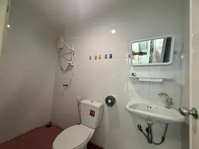 a white bathroom with a toilet and a sink at Cha Cha Guesthouse in Patong Beach