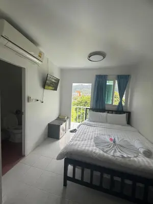 a bedroom with a bed with blue curtains and a window at Cha Cha Guesthouse in Patong Beach