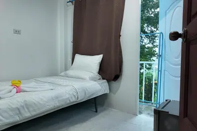 a bed sitting in a room with a window at Cha Cha Guesthouse in Patong Beach