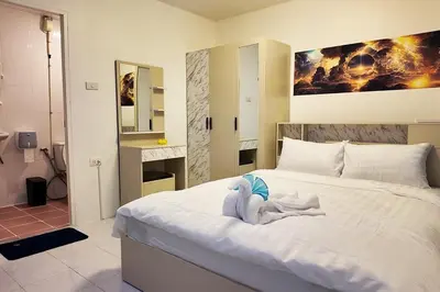 a bedroom with a white bed with a stuffed animal on it at Cha Cha Guesthouse in Patong Beach