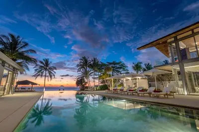 a resort pool with chairs and a view of the ocean at Villa Malee Sai in Ban Han Pa To