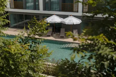two umbrellas and chairs next to a swimming pool at 1 Bedroom 108-114 Pool View at Ozone Laguna near Bangtao Beach and Golf in Bang Tao Beach