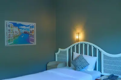 a bedroom with a white bed and a picture on the wall at Nora Bukit Hotel in Ban Sam Kong