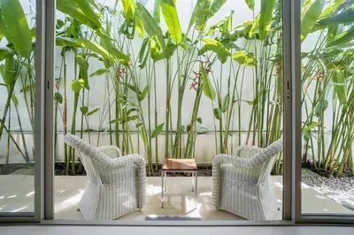 two chairs and a table in a room with plants at Stylish 3BR Pool Villa trichada Airport Shuttle in Phuket Town