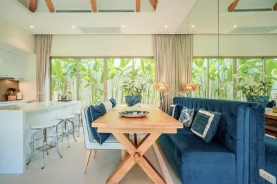 a living room with a blue couch and a table at Stylish 3BR Pool Villa trichada Airport Shuttle in Phuket Town