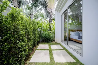 an internal garden with a courtyard with a bed and plants at Private 3BR Villa trichad Airport and Maid in Phuket Town