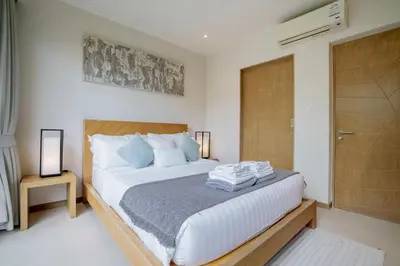 a bedroom with a bed with white sheets and blue pillows at Private 3BR Villa trichad Airport and Maid in Phuket Town