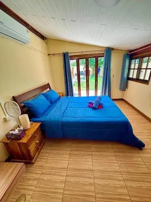 a bedroom with a blue bed and a window at The glade in Ko Yao Noi