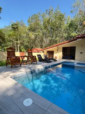 a swimming pool with two chairs and a table at The glade in Ko Yao Noi