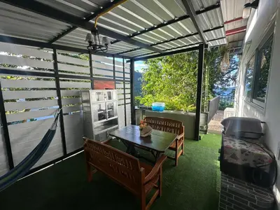 a screened in porch with a table and benches at Maison Paradise Sea View in Patong Beach