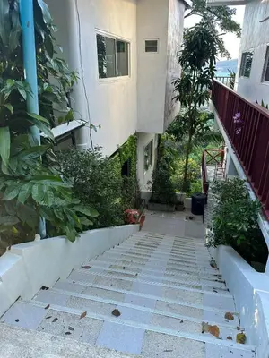 a stairway leading to a white building with trees at Maison Paradise Sea View in Patong Beach