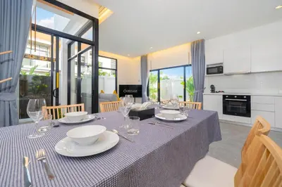 a dining room with a table with plates and wine glasses at Villa Serana - New Private Pool Villa in Goldena Residence, Kamala in Kamala Beach