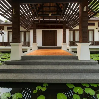 a building with stairs leading to a door and a pond at Tropical Thai Loft with Koi Pond in Kamala Beach