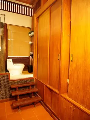 a bathroom with wooden cabinets and a toilet at Tropical Thai Loft with Koi Pond in Kamala Beach