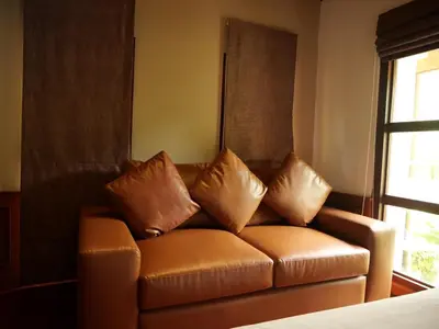 a brown leather couch with three pillows on it at Tropical Thai Loft with Koi Pond in Kamala Beach