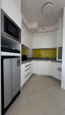 a large kitchen with white cabinets and a microwave at Cassia Sea and Pool view 2bd apartments by Aster in Laguna Phuket