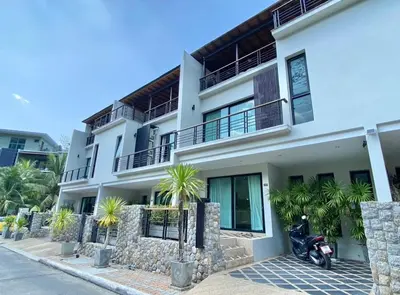 a white house with a motorcycle parked in front of it at Villa Nature village kamala in Kamala Beach