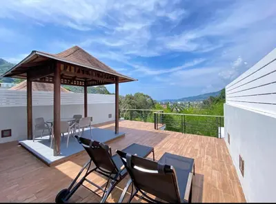 a wooden deck with chairs and a gazebo at Villa Nature village kamala in Kamala Beach