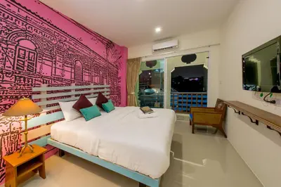 a bedroom with a large bed with a pink wall at The Pho Thong Phuket in Phuket Town
