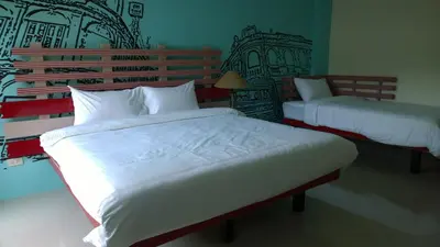 a bedroom with two beds with white comforters and a wall at The Pho Thong Phuket in Phuket Town