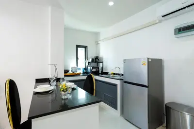 a kitchen with a table and a refrigerator at New! bayfront 2 BR Villa with private pool Nariya V1 - rare find in Phuket in Chalong