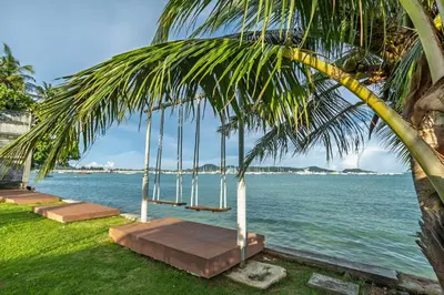 a swing hanging from a palm tree next to the water at New! bayfront 2 BR Villa with private pool Nariya V1 - rare find in Phuket in Chalong