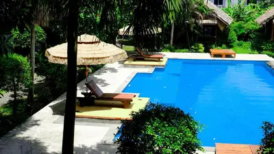 a swimming pool with two lounge chairs and an umbrella at Bora Bora Villa Phuket in Chalong