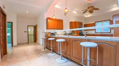 a kitchen with wooden cabinets and bar stools at Golfer's Getaway 7 Bedroom Pool Villa (SV1) in Phuket Town