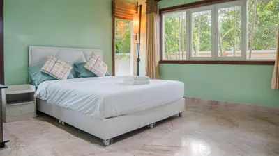 a bedroom with a white bed in a room with windows at Golfer's Getaway 7 Bedroom Pool Villa (SV1) in Phuket Town