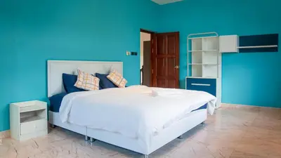 a blue bedroom with a white bed and a blue wall at Golfer's Getaway 7 Bedroom Pool Villa (SV1) in Phuket Town