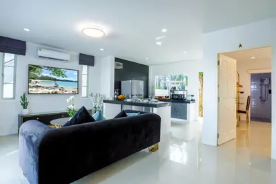 a living room with a black couch and a kitchen at Exclusive! 3-Bedroom Pool Villa with Bay View-Nariya V8 in Chalong
