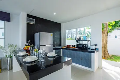 a kitchen with blue cabinets and a black counter top at Exclusive! 3-Bedroom Pool Villa with Bay View-Nariya V8 in Chalong