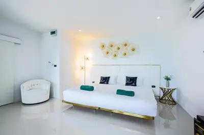 a white bedroom with a large bed and a chair at Exclusive! 3-Bedroom Pool Villa with Bay View-Nariya V8 in Chalong