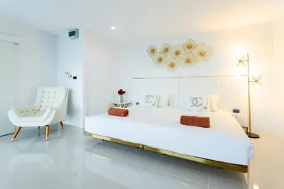 a white bedroom with a large bed and a white chair at NEW! 3-Bedroom Pool Villa Overlooking Chalong Bay-Nariya V9 in Chalong